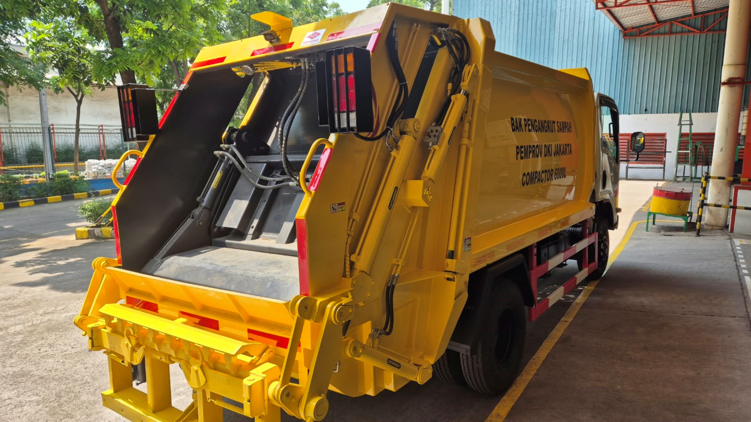 Compactor garbage truck di depo sampah dengan latar tropis Indonesia